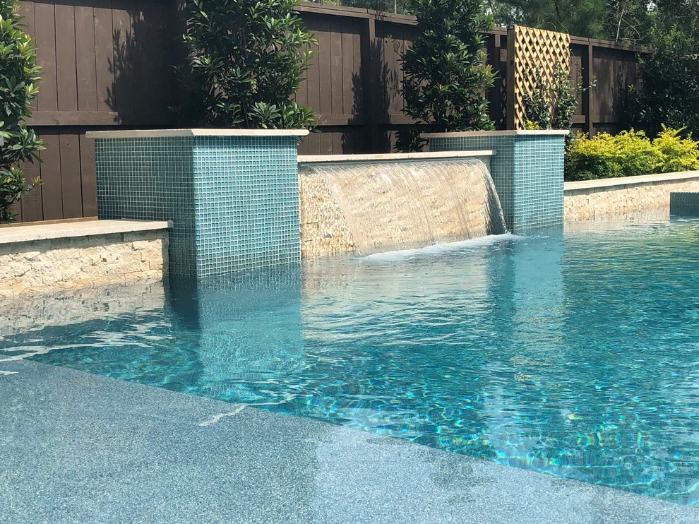 Modelo de piscinas y jacuzzis alargados tradicionales grandes en forma de L en patio trasero con adoquines de piedra natural