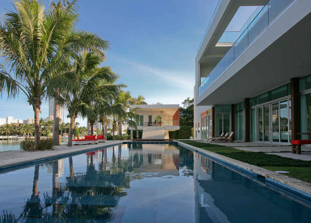 Idee per una grande piscina monocorsia minimalista rettangolare dietro casa con una dépendance a bordo piscina e pavimentazioni in pietra naturale