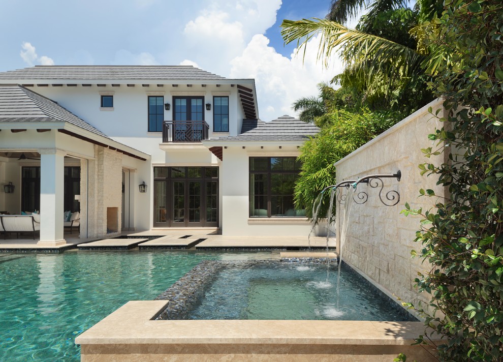 Diseño de piscina con fuente infinita tradicional renovada grande a medida en patio trasero con adoquines de piedra natural