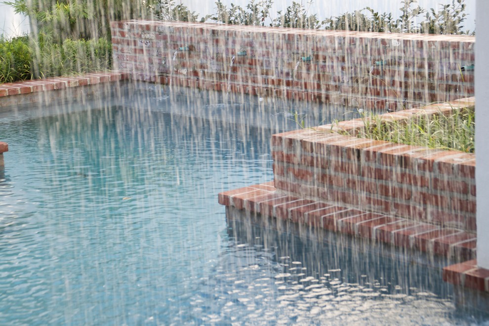Ispirazione per una piscina monocorsia chic rettangolare di medie dimensioni e dietro casa con fontane e pavimentazioni in mattoni
