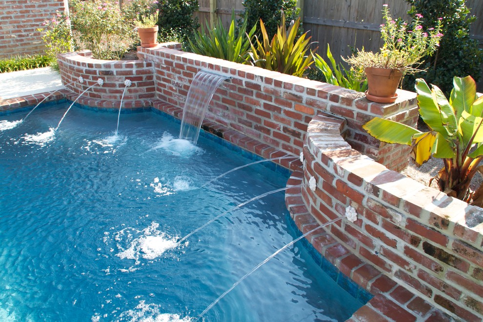 Modelo de piscina con fuente alargada clásica de tamaño medio rectangular en patio trasero con adoquines de ladrillo