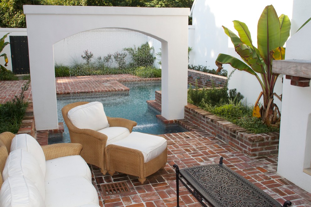 Modelo de piscina con fuente alargada tradicional de tamaño medio rectangular en patio trasero con adoquines de ladrillo