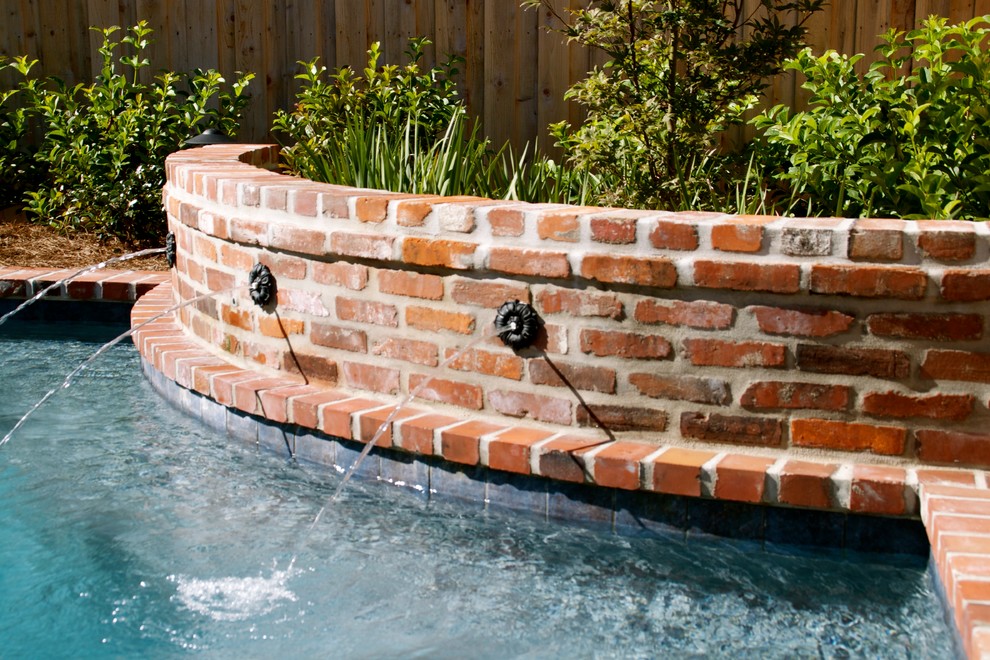 Medium sized traditional back custom shaped lengths hot tub in New Orleans with brick paving.