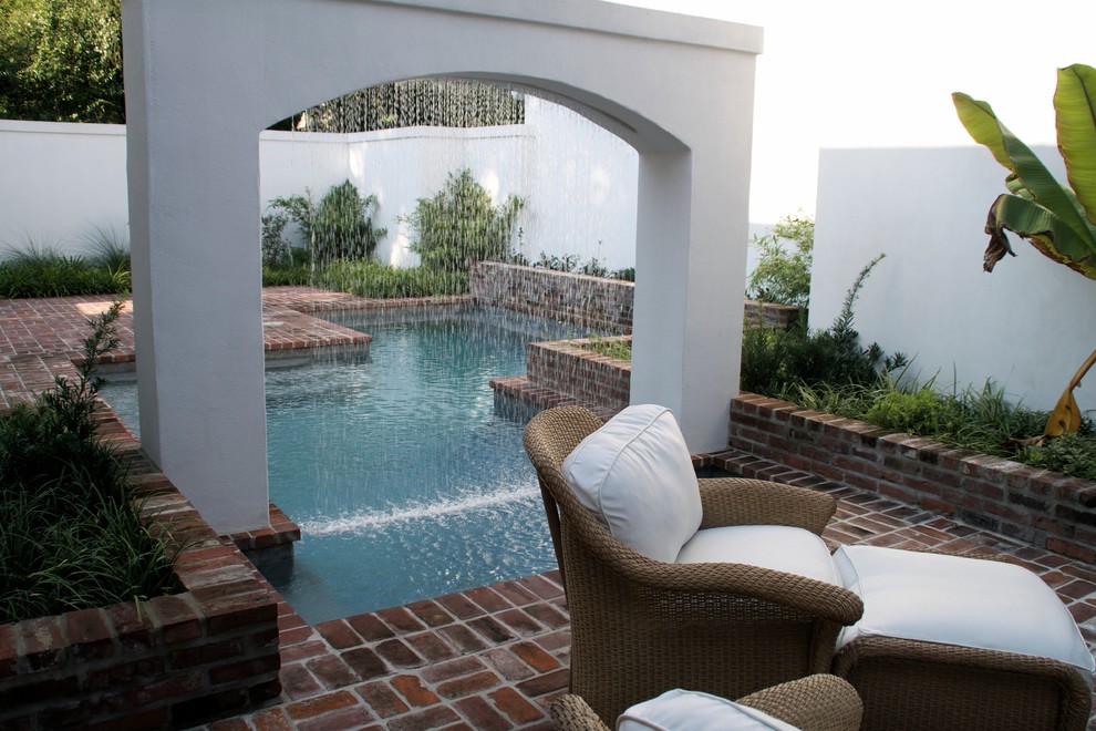Diseño de piscina con fuente alargada clásica de tamaño medio rectangular en patio trasero con adoquines de ladrillo