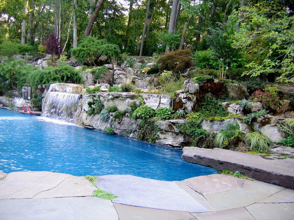 Cette image montre une très grande piscine naturelle et arrière ethnique sur mesure avec un point d'eau et des pavés en pierre naturelle.