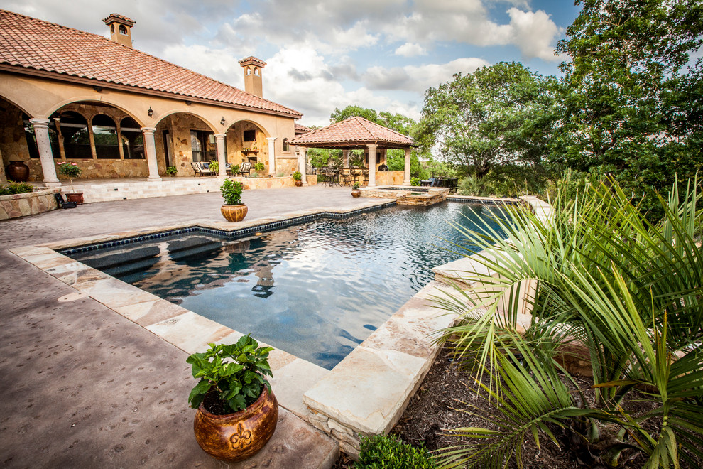 Inspiration for a large mediterranean back rectangular hot tub in Austin with natural stone paving.