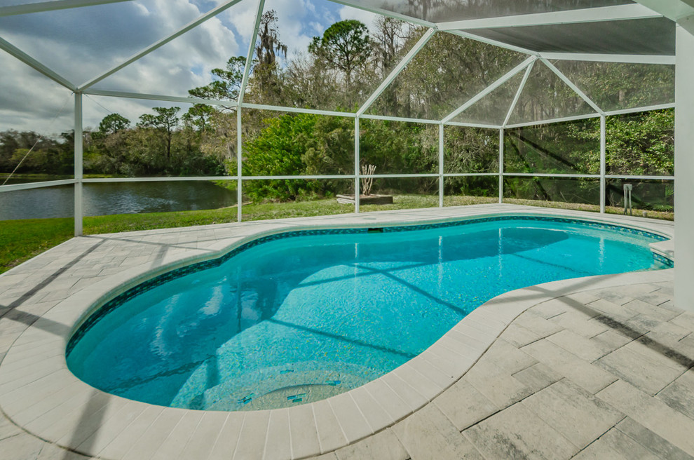 Immagine di una piscina naturale costiera a "C" di medie dimensioni e dietro casa con pedane