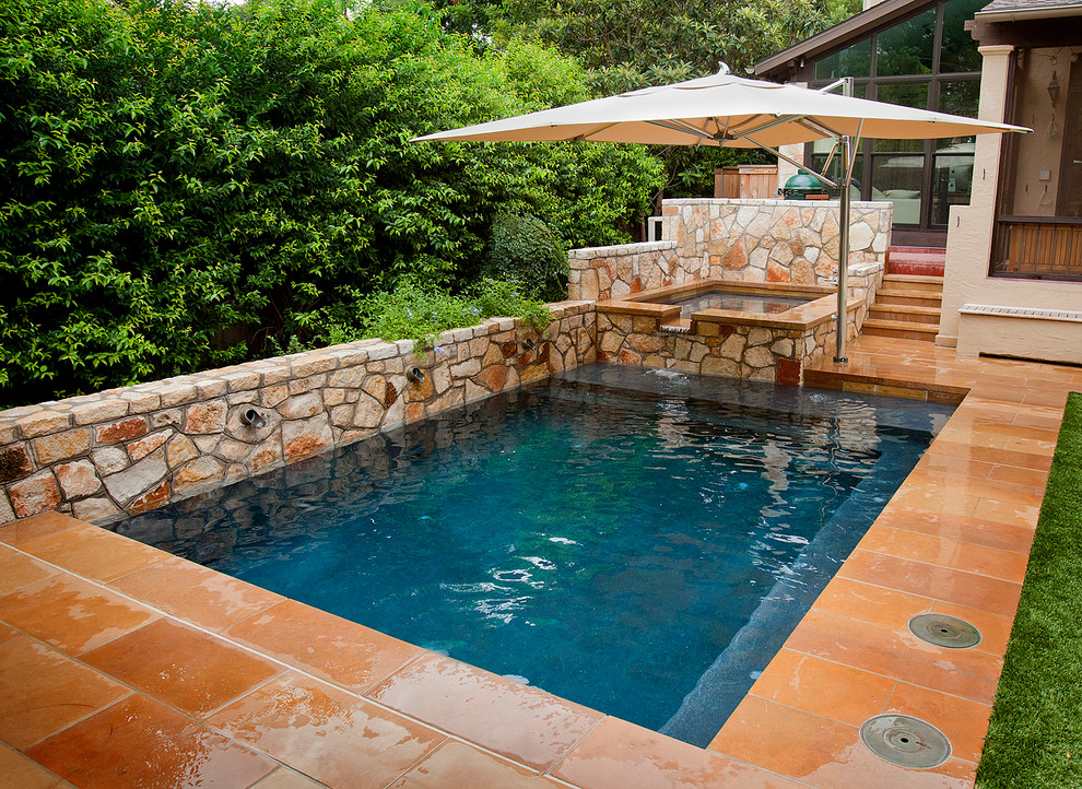 Immagine di una piccola piscina monocorsia chic rettangolare dietro casa con pavimentazioni in pietra naturale e una vasca idromassaggio