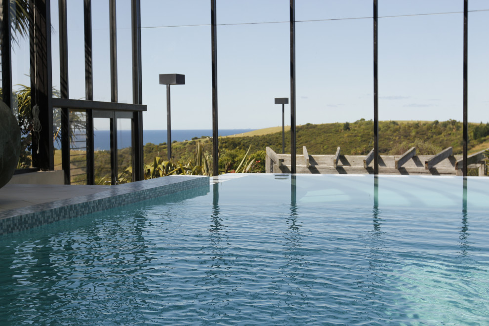 Foto di una grande piscina coperta a sfioro infinito design personalizzata con piastrelle