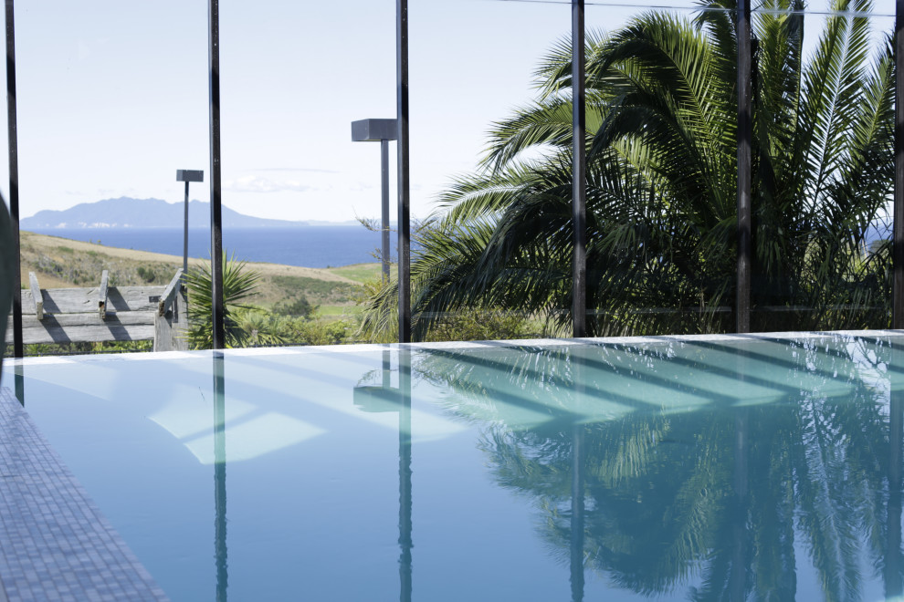 Foto di una grande piscina coperta a sfioro infinito minimal personalizzata con piastrelle