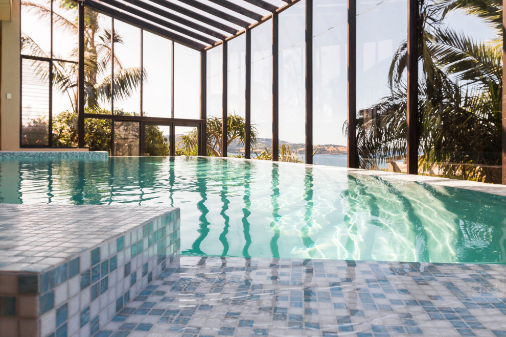 Immagine di una grande piscina coperta a sfioro infinito minimal personalizzata con piastrelle