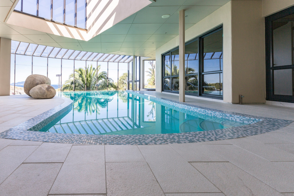 Inspiration for a large contemporary indoor private and custom shaped infinity swimming pool in Auckland with tiled flooring.