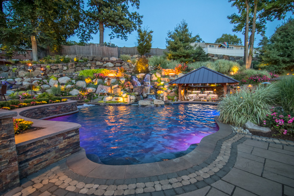 Photo of an expansive back custom shaped natural hot tub in New York with concrete paving.