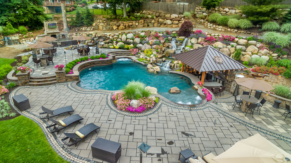 Ejemplo de piscinas y jacuzzis naturales extra grandes a medida en patio trasero con adoquines de hormigón