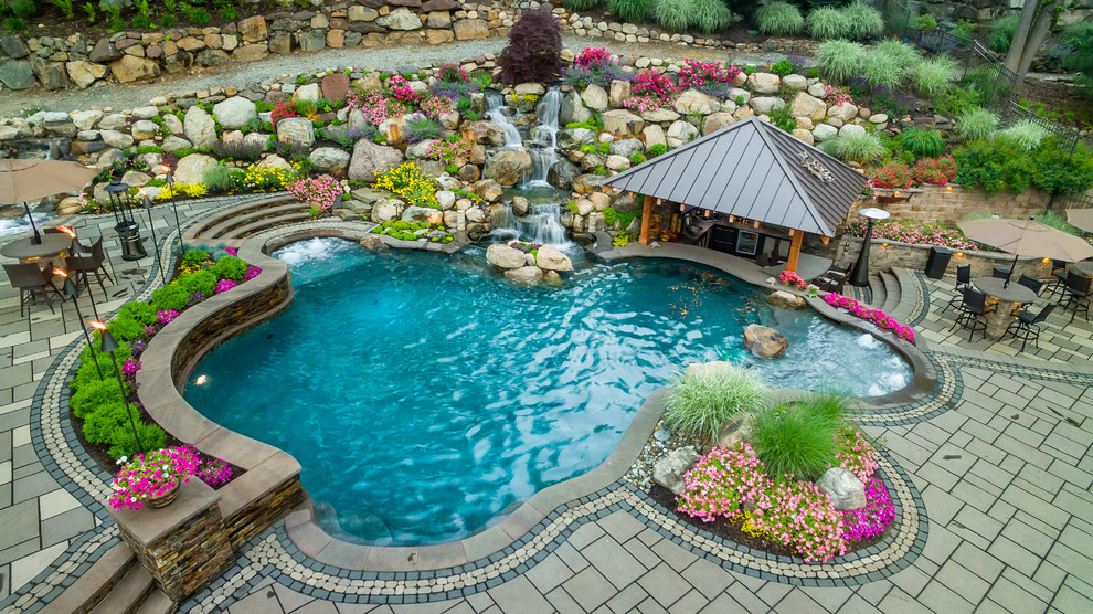 Foto de piscinas y jacuzzis naturales extra grandes a medida en patio trasero con adoquines de hormigón
