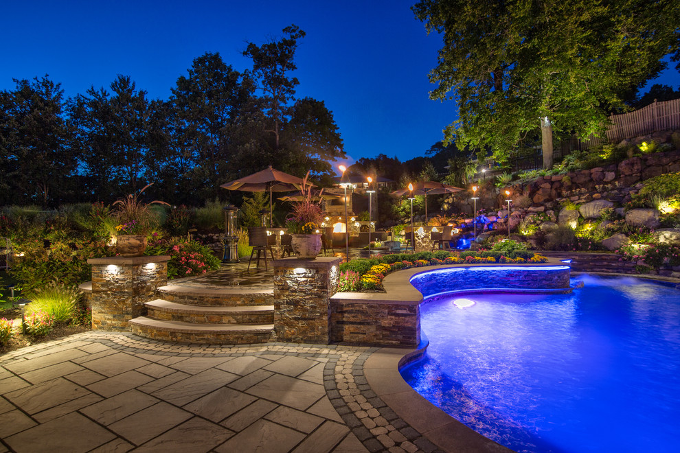 Diseño de piscinas y jacuzzis naturales extra grandes a medida en patio trasero con adoquines de hormigón