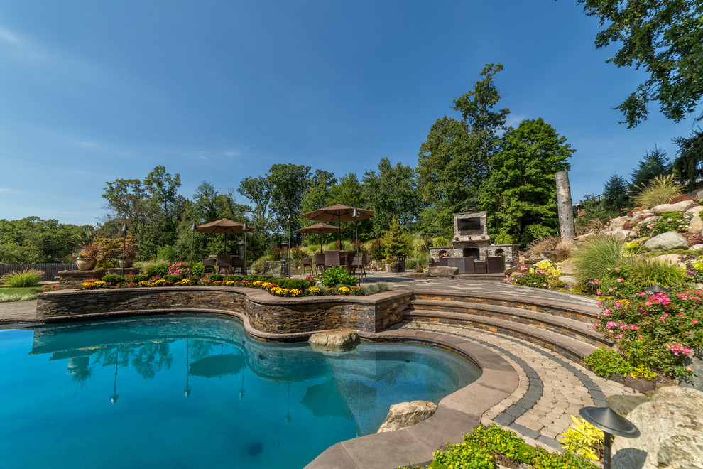Imagen de piscinas y jacuzzis naturales extra grandes a medida en patio trasero con adoquines de hormigón