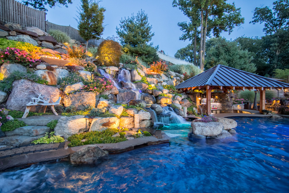 Diseño de piscinas y jacuzzis naturales extra grandes a medida en patio trasero con adoquines de hormigón