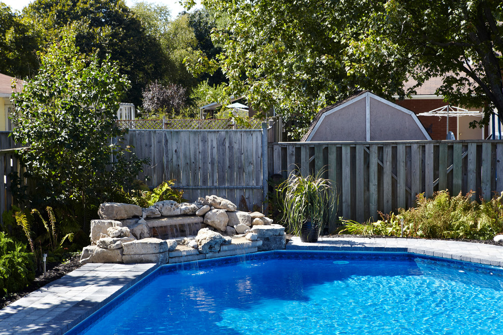 Ispirazione per una piscina naturale tradizionale personalizzata di medie dimensioni e dietro casa con pavimentazioni in mattoni e fontane