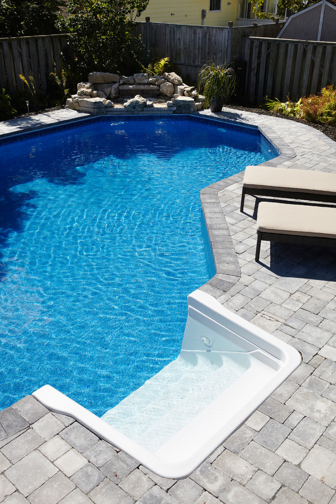 Foto de piscina con fuente natural clásica de tamaño medio a medida en patio trasero con adoquines de ladrillo