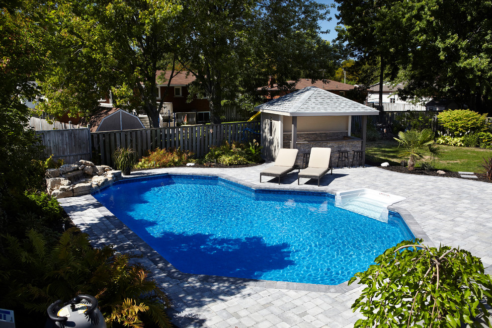 Esempio di una piscina naturale tradizionale personalizzata di medie dimensioni e dietro casa con pavimentazioni in mattoni e fontane