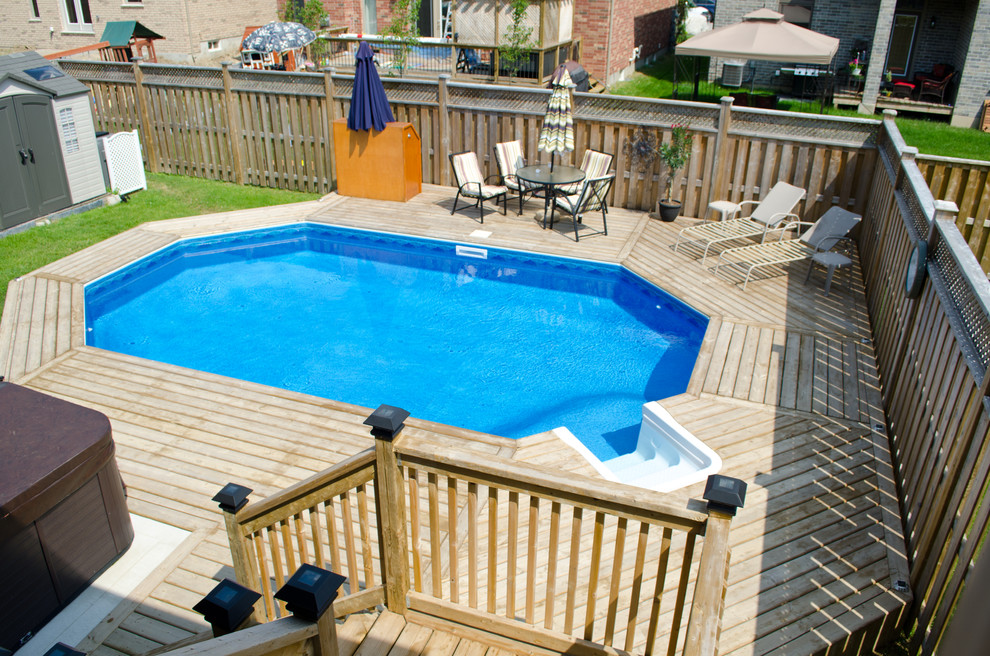 Modelo de piscina natural tradicional de tamaño medio a medida en patio trasero con entablado