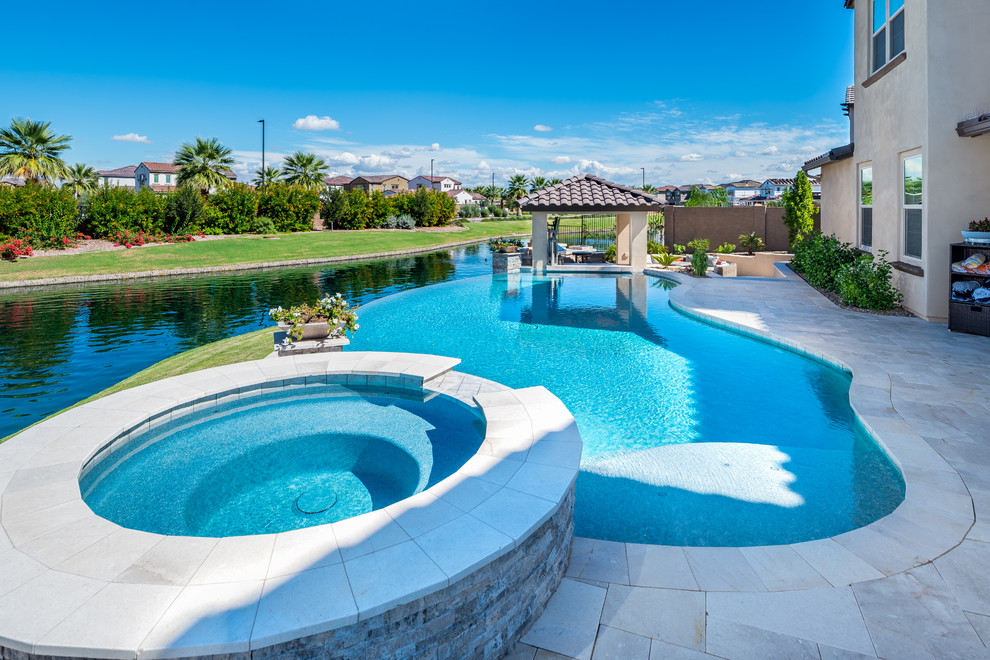 Foto di una piscina a sfioro infinito design a "C" di medie dimensioni e dietro casa con una vasca idromassaggio e piastrelle
