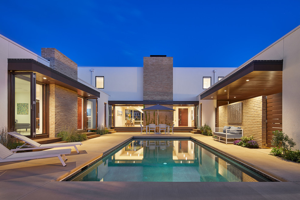 Стильный дизайн: большой прямоугольный бассейн на внутреннем дворе в стиле модернизм с джакузи и покрытием из бетонных плит - последний тренд