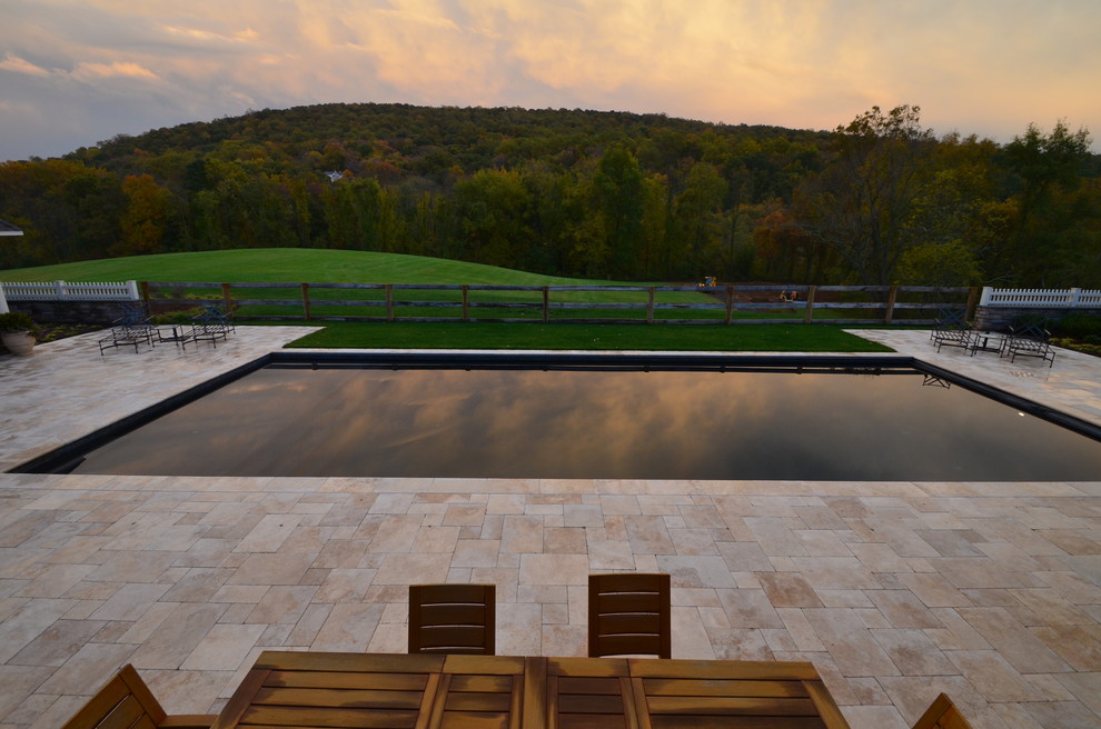 Imagen de piscina alargada de estilo americano grande rectangular en patio trasero con adoquines de piedra natural