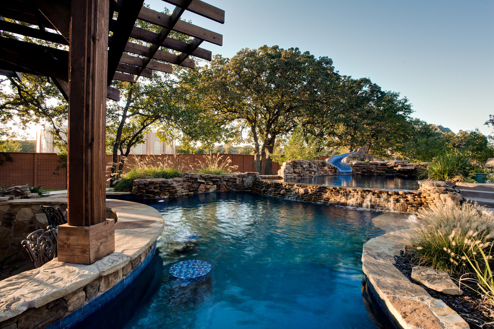 Идея дизайна: огромный естественный бассейн произвольной формы на заднем дворе в морском стиле с водной горкой и покрытием из каменной брусчатки