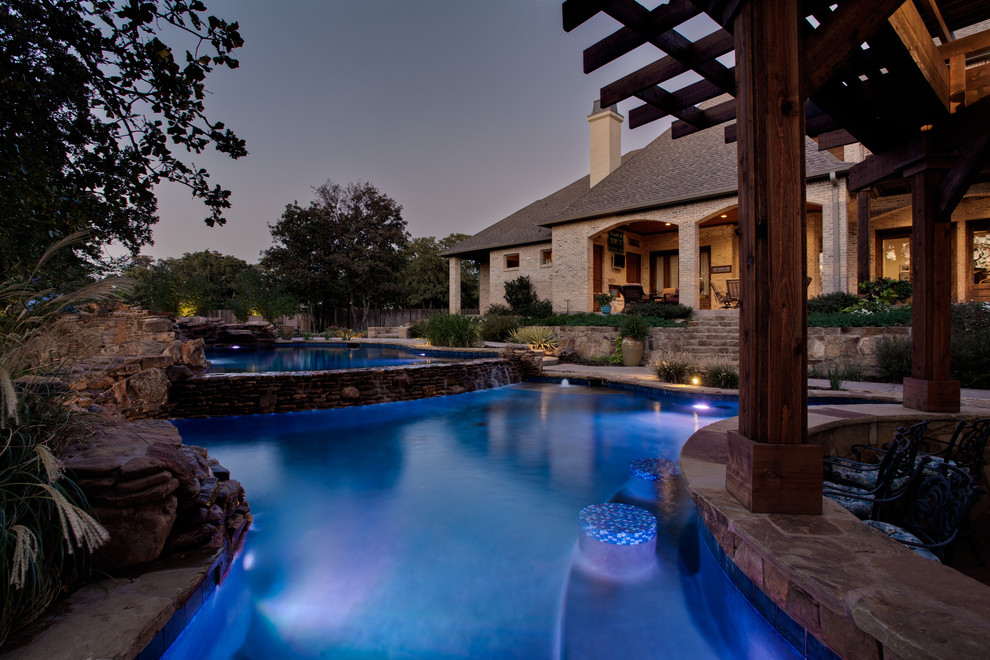 Pool fountain - huge tropical backyard stone and custom-shaped natural pool fountain idea in Dallas