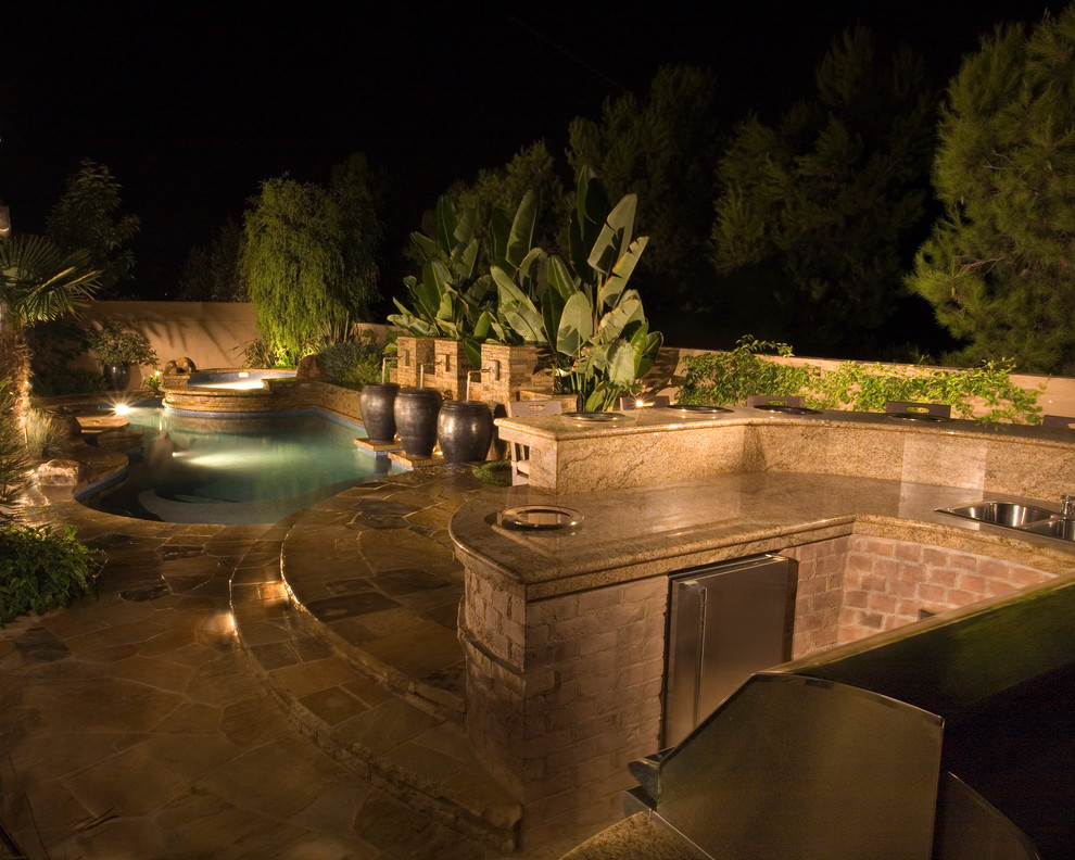 На фото: большой бассейн произвольной формы на заднем дворе в средиземноморском стиле с зоной барбекю с