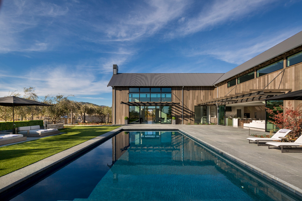 Ispirazione per un'ampia piscina monocorsia country rettangolare dietro casa con pavimentazioni in pietra naturale