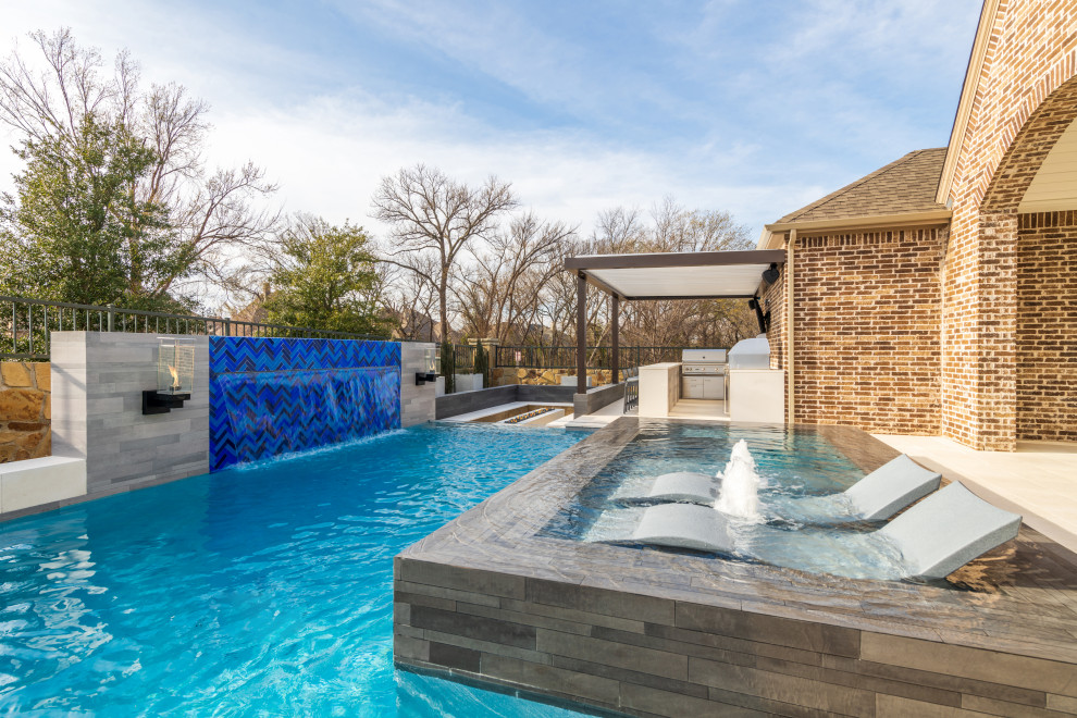 Diseño de piscinas y jacuzzis actuales grandes rectangulares en patio trasero con adoquines de piedra natural