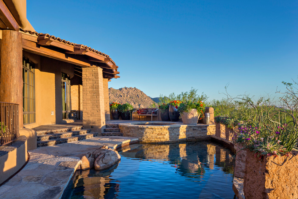 This is an example of a medium sized back custom shaped natural swimming pool in Phoenix with natural stone paving.