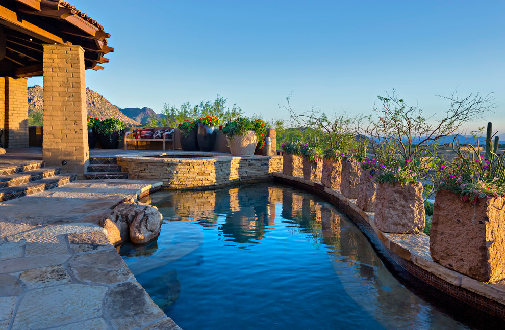 Ejemplo de piscina de estilo americano de tamaño medio en patio trasero con adoquines de piedra natural