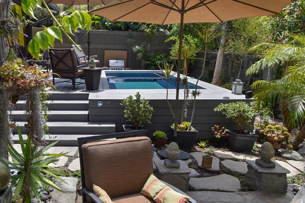 Modelo de piscina tropical pequeña rectangular en patio trasero con entablado