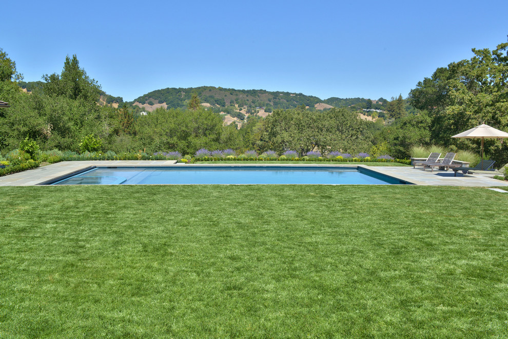 Diseño de piscinas y jacuzzis alargados de estilo americano grandes rectangulares en patio trasero con adoquines de hormigón