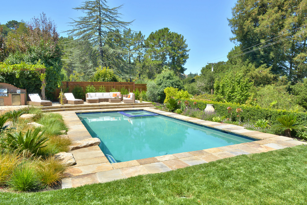 Immagine di una piscina monocorsia mediterranea rettangolare di medie dimensioni e dietro casa con una vasca idromassaggio e pavimentazioni in pietra naturale