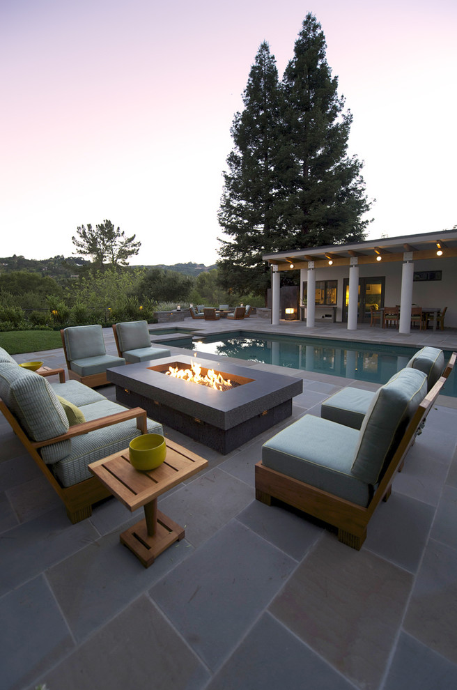 Foto de piscina alargada contemporánea rectangular en patio trasero con adoquines de piedra natural