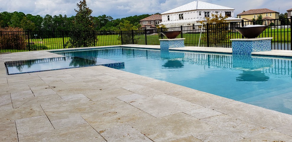 Modelo de piscinas y jacuzzis alargados modernos de tamaño medio rectangulares en patio trasero con adoquines de piedra natural