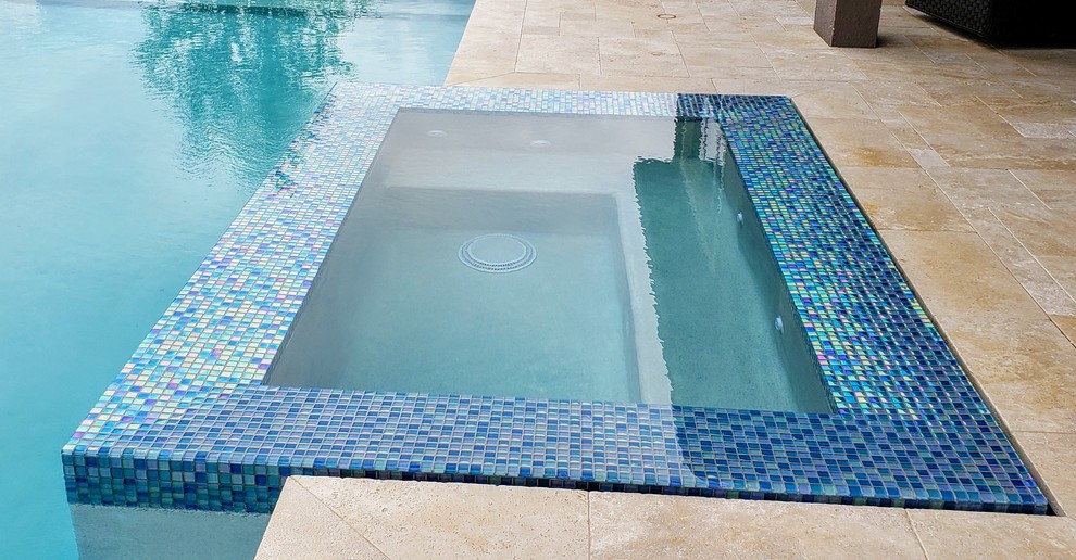 Foto di una piscina monocorsia minimalista rettangolare di medie dimensioni e dietro casa con una vasca idromassaggio e pavimentazioni in pietra naturale