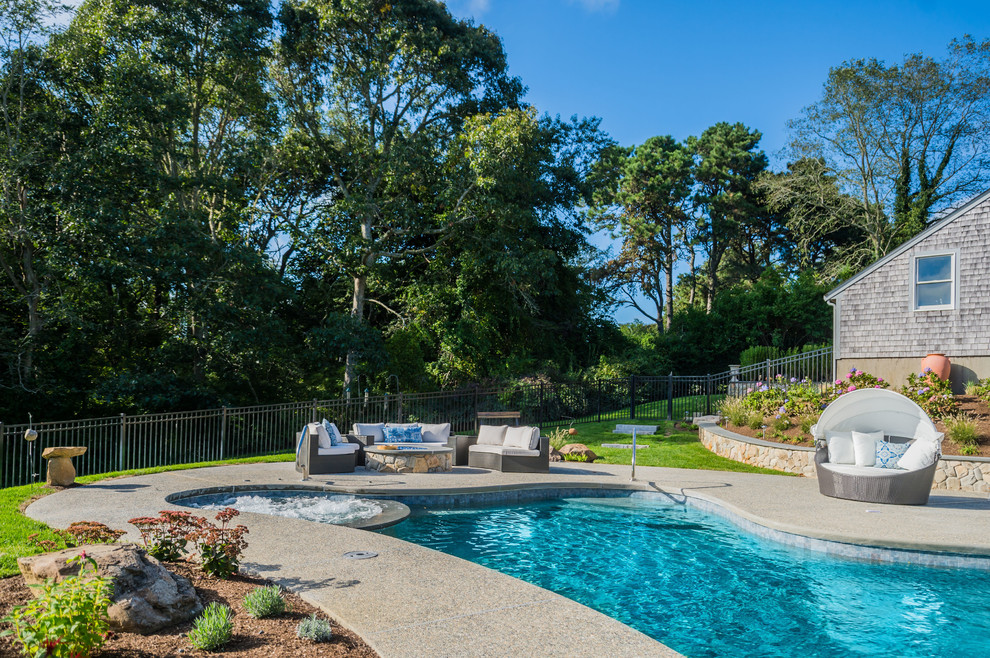 This is an example of a medium sized bohemian back custom shaped natural swimming pool in Boston with concrete slabs.