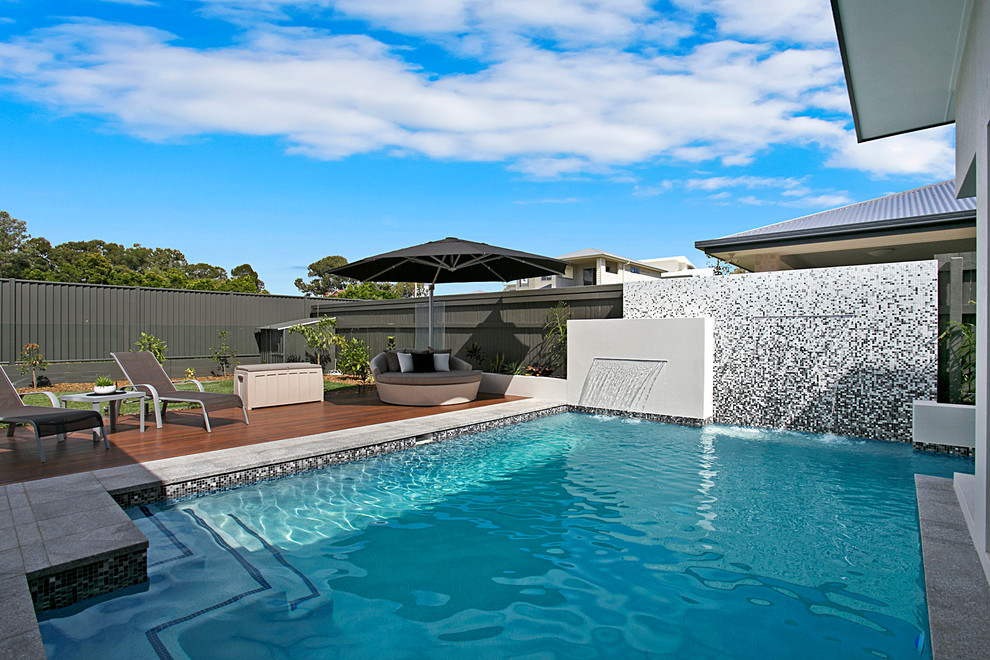 Immagine di una piscina monocorsia minimalista a "L" di medie dimensioni e dietro casa con fontane e pedane
