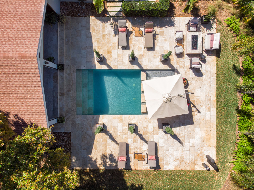 Imagen de piscina tradicional de tamaño medio rectangular en patio trasero con adoquines de piedra natural