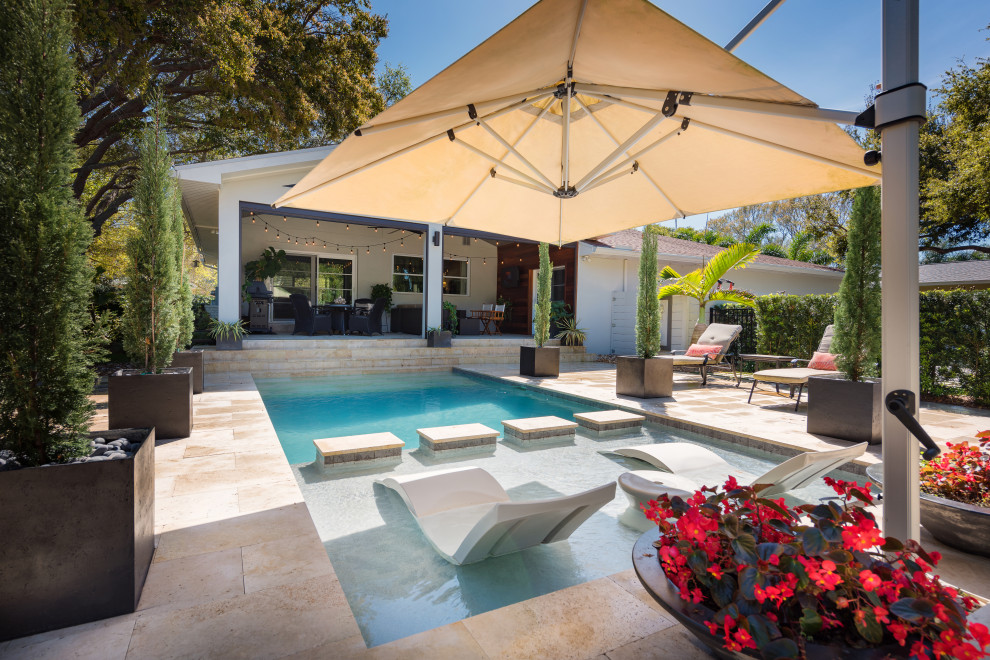 Imagen de piscina clásica de tamaño medio rectangular en patio trasero con adoquines de piedra natural