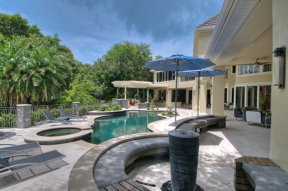 Ispirazione per un'ampia piscina design dietro casa con pavimentazioni in pietra naturale e una vasca idromassaggio