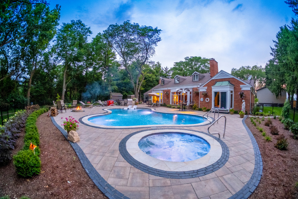 Esempio di una piscina classica personalizzata di medie dimensioni e dietro casa con una vasca idromassaggio e pavimentazioni in pietra naturale