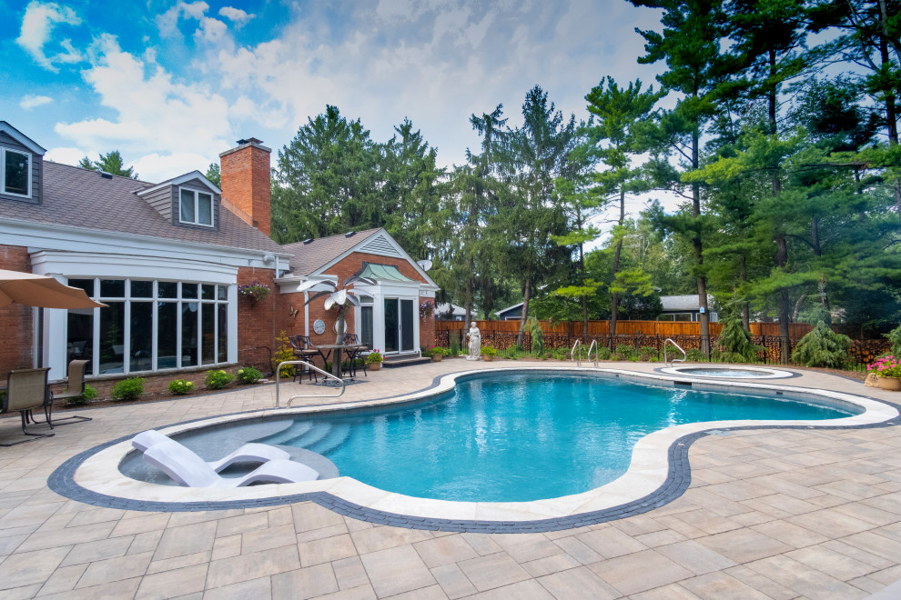 Immagine di una piscina tradizionale personalizzata di medie dimensioni e dietro casa con una vasca idromassaggio e pavimentazioni in pietra naturale