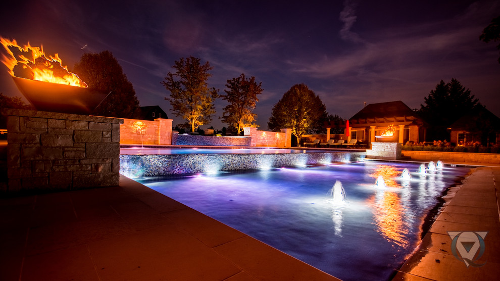 Immagine di una grande piscina a sfioro infinito chic rettangolare dietro casa con fontane e pavimentazioni in pietra naturale